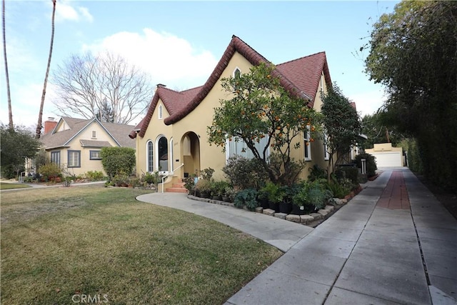 english style home with a front lawn and stucco siding
