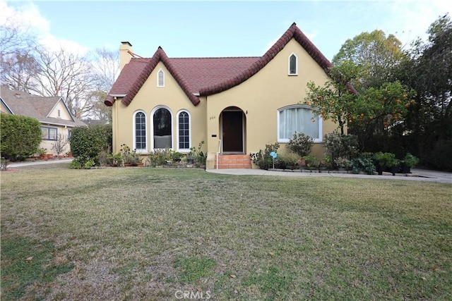 view of front of house featuring a chimney, a front lawn, and stucco siding