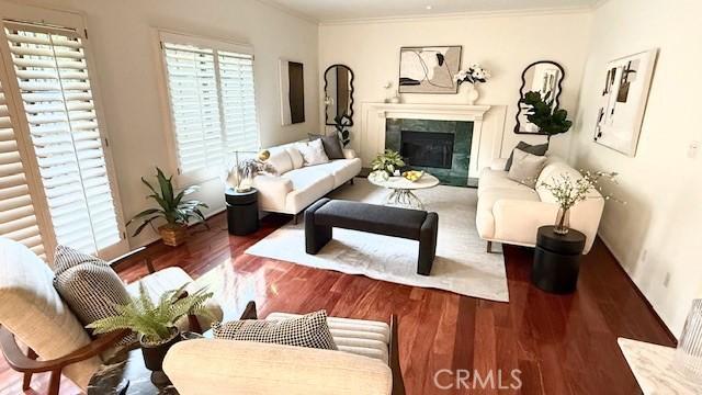 living area with ornamental molding, wood finished floors, and a fireplace