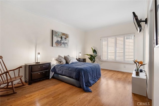 bedroom featuring baseboards, crown molding, and light wood-type flooring