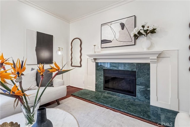 living area with baseboards, ornamental molding, wood finished floors, and a fireplace
