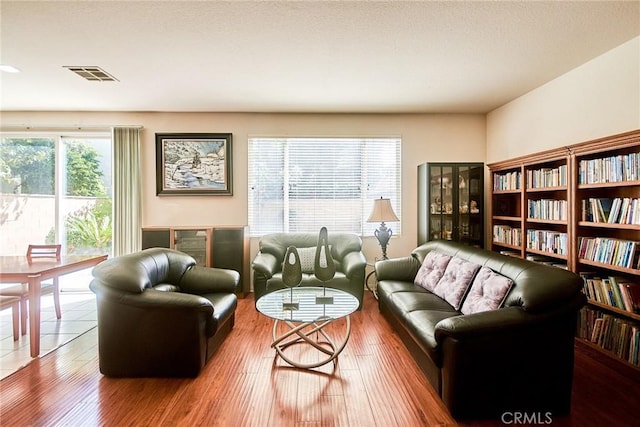 living area featuring visible vents and wood finished floors