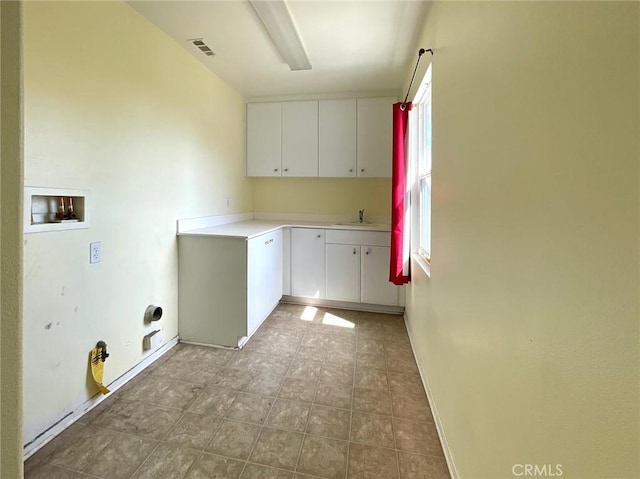 clothes washing area with hookup for a washing machine, visible vents, a sink, baseboards, and cabinet space