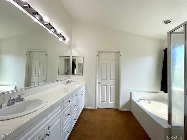 bathroom featuring double vanity, a garden tub, vaulted ceiling, and a sink