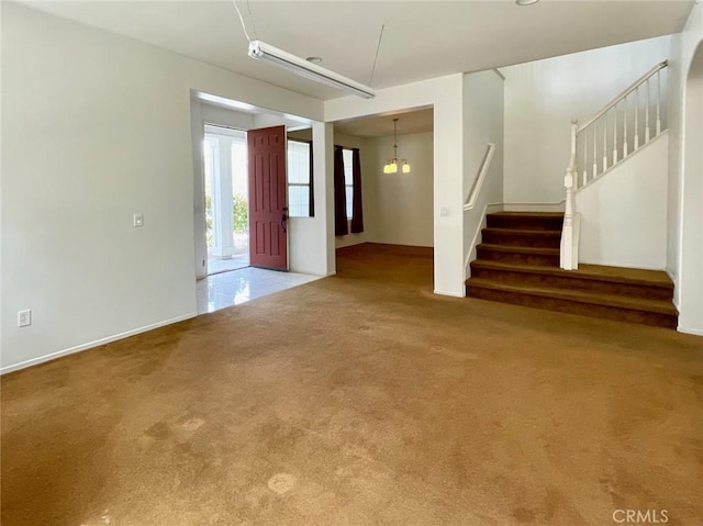 unfurnished living room with an inviting chandelier, stairs, baseboards, and carpet floors