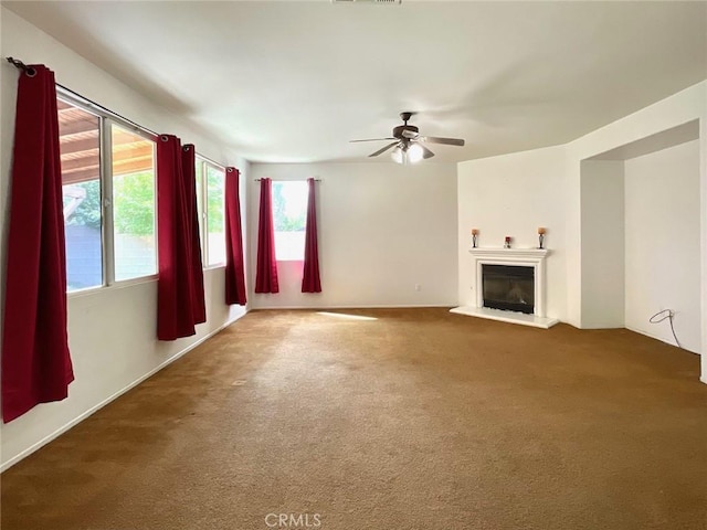 unfurnished living room with a glass covered fireplace, carpet flooring, visible vents, and ceiling fan