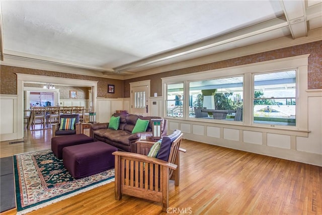 living room with a wainscoted wall, beam ceiling, and wood finished floors