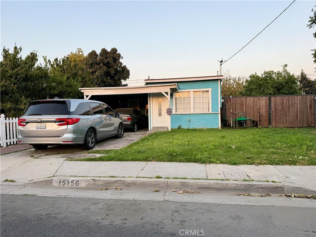 view of front of property featuring a carport, driveway, a front yard, and fence
