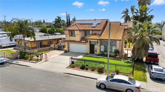 1010 W Wilson St, Pomona, CA 91768 - view of front of home with a fenced front yard, solar panels, an attached garage, a tile roof, and driveway
