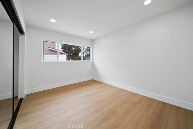 unfurnished bedroom with baseboards, a closet, recessed lighting, and wood finished floors