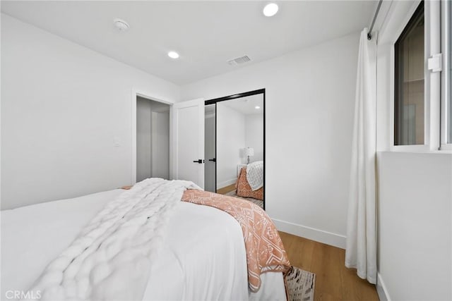 bedroom with visible vents, a closet, wood finished floors, baseboards, and recessed lighting