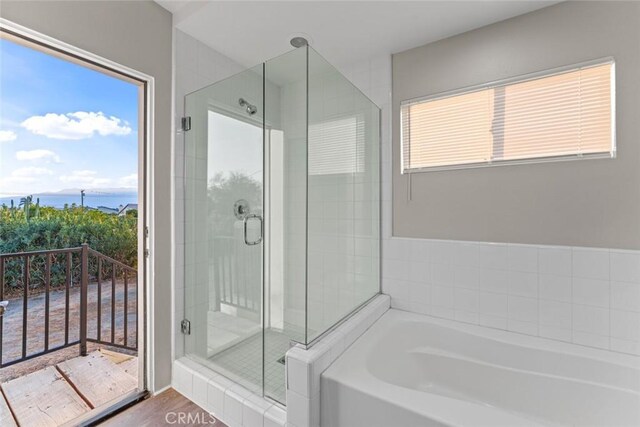 full bath featuring a shower stall, a garden tub, and wood finished floors