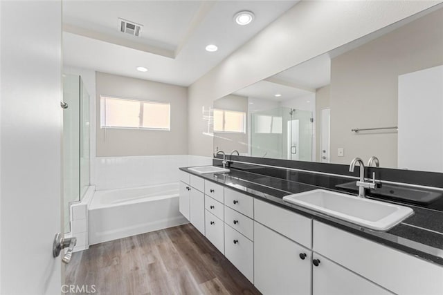 bathroom with visible vents, a sink, recessed lighting, a shower stall, and wood finished floors