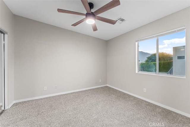 carpeted empty room with visible vents, baseboards, and ceiling fan