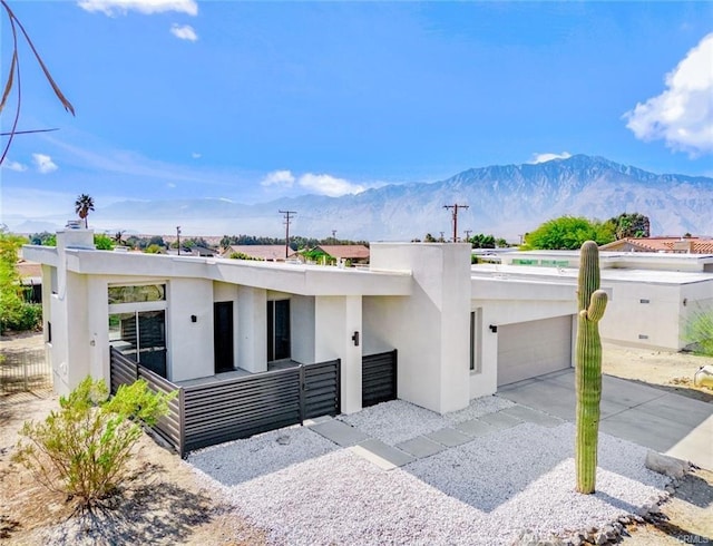 view of front of property with stucco siding, a mountain view, driveway, an attached garage, and fence