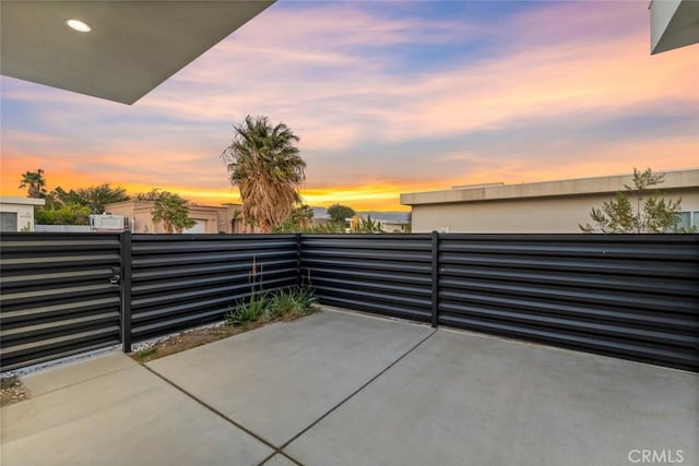 patio terrace at dusk featuring a balcony