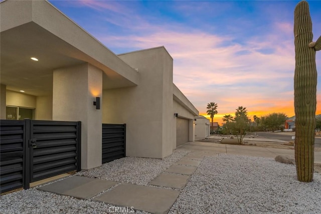 view of side of property featuring a garage, driveway, and stucco siding