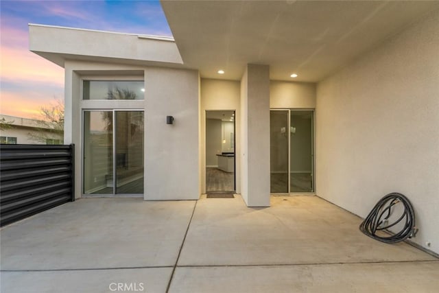 view of exterior entry with a patio and stucco siding