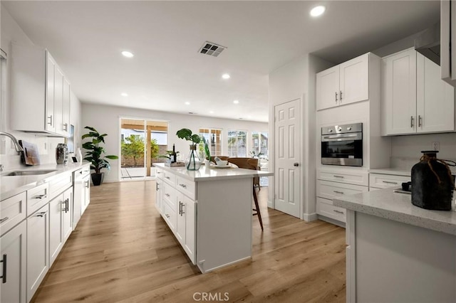 12949 Colonial Dr, Rancho Cucamonga, CA 91739 - kitchen with light wood-style floors, visible vents, a center island, a sink, and oven