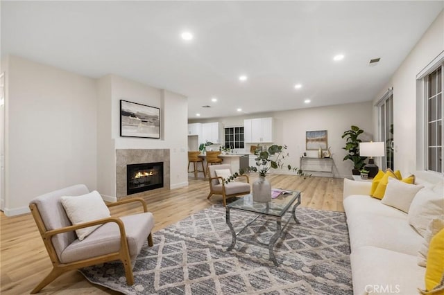 12949 Colonial Dr, Rancho Cucamonga, CA 91739 - living room featuring light wood-style floors, a tiled fireplace, baseboards, and recessed lighting