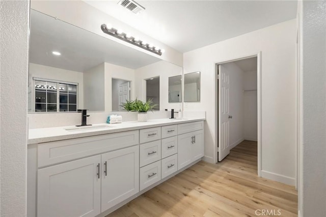 12949 Colonial Dr, Rancho Cucamonga, CA 91739 - bathroom with visible vents, wood finished floors, a sink, double vanity, and baseboards