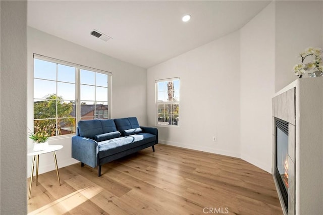 12949 Colonial Dr, Rancho Cucamonga, CA 91739 - sitting room with a glass covered fireplace, baseboards, vaulted ceiling, visible vents, and light wood finished floors