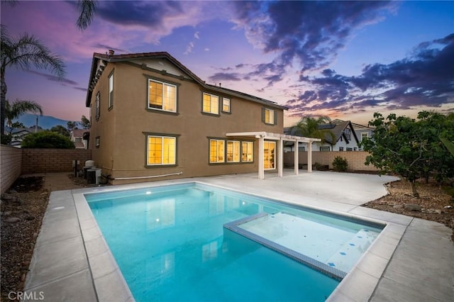 12949 Colonial Dr, Rancho Cucamonga, CA 91739 - back of property at dusk with stucco siding, a pergola, a patio area, central AC unit, and a fenced backyard