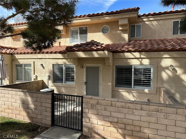 mediterranean / spanish home with a tile roof, a gate, and a fenced front yard
