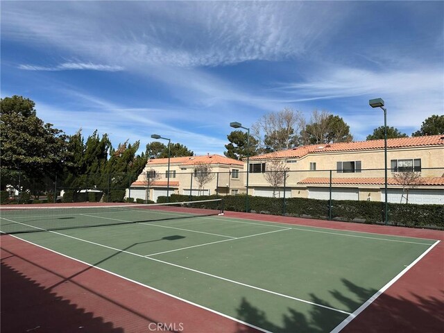 view of tennis court with community basketball court and fence