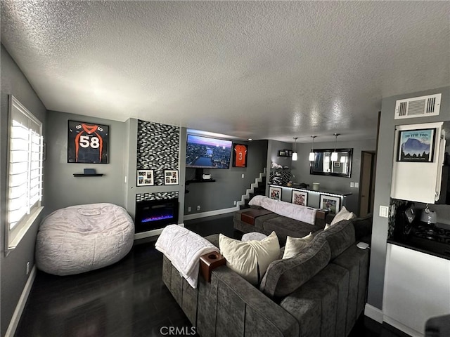 living area with visible vents, baseboards, stairway, and a textured ceiling