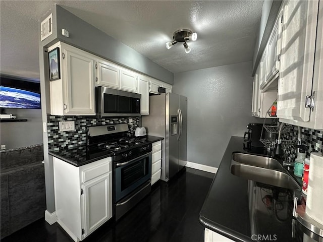 kitchen featuring dark countertops, tasteful backsplash, a textured ceiling, and appliances with stainless steel finishes