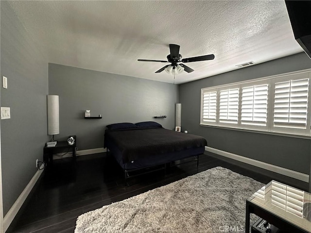 bedroom with visible vents, baseboards, a textured ceiling, and wood finished floors