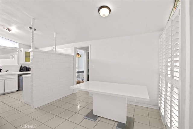 interior space with light tile patterned floors, white cabinetry, a sink, and light countertops