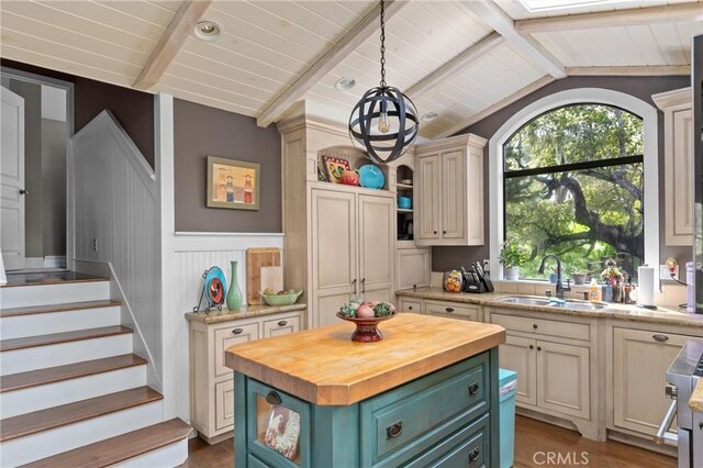 kitchen with a sink, butcher block countertops, lofted ceiling with beams, a wainscoted wall, and wood ceiling
