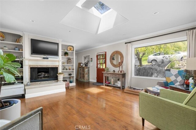living area featuring recessed lighting, built in shelves, ornamental molding, a skylight, and wood finished floors