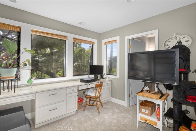 home office featuring baseboards, built in study area, and light carpet