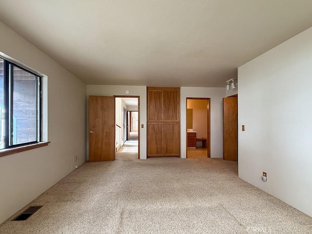 unfurnished bedroom with visible vents, carpet flooring, and ensuite bath
