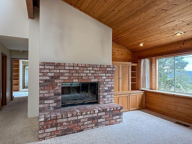 unfurnished living room with visible vents, wood ceiling, wooden walls, carpet floors, and vaulted ceiling