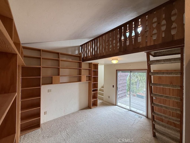 unfurnished living room featuring visible vents, a textured ceiling, stairway, carpet flooring, and lofted ceiling