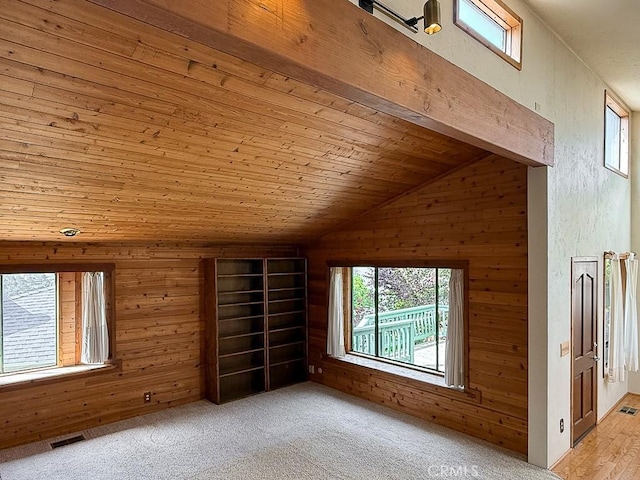additional living space with wood walls, visible vents, and lofted ceiling