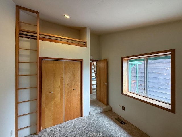 unfurnished bedroom featuring visible vents, carpet flooring, and a closet