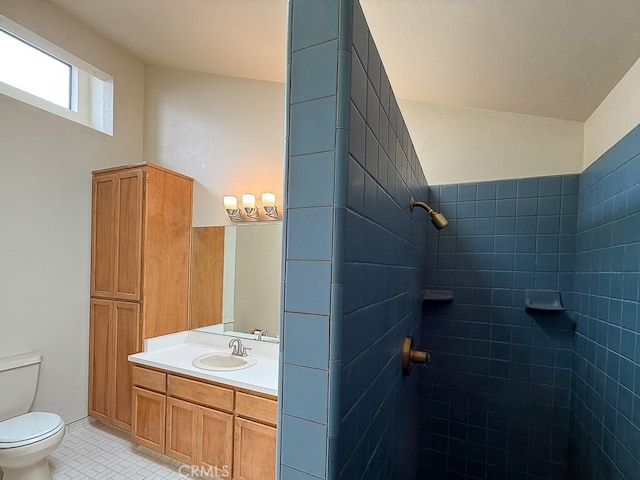 bathroom with a tile shower, tile patterned floors, toilet, and vanity