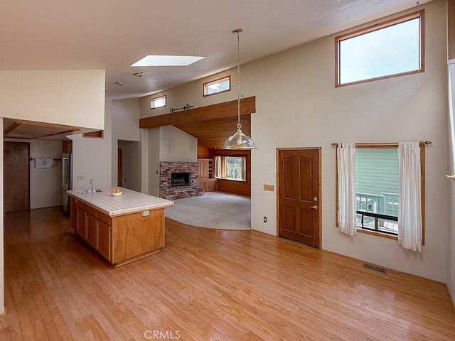 kitchen featuring a sink, visible vents, light wood-type flooring, and a fireplace