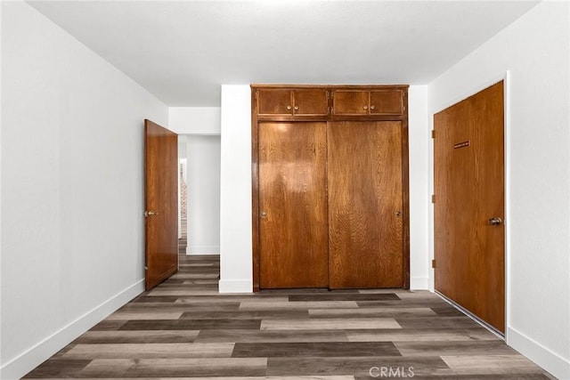 unfurnished bedroom with baseboards, wood finished floors, and a closet