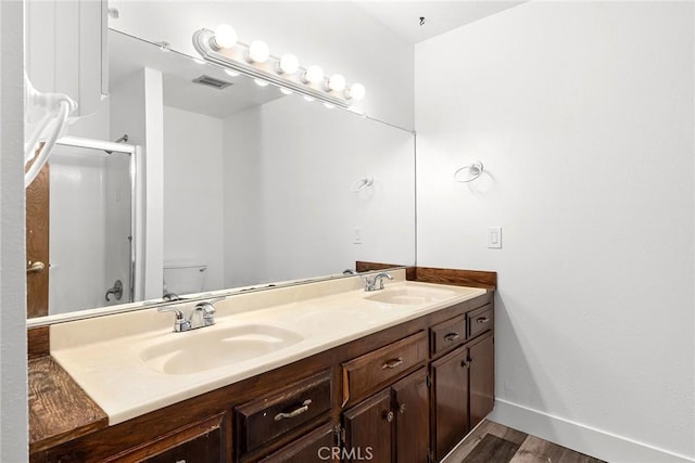 bathroom with wood finished floors, a sink, visible vents, and double vanity