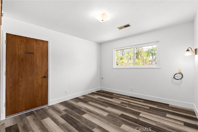 unfurnished room with dark wood-style floors, baseboards, and visible vents
