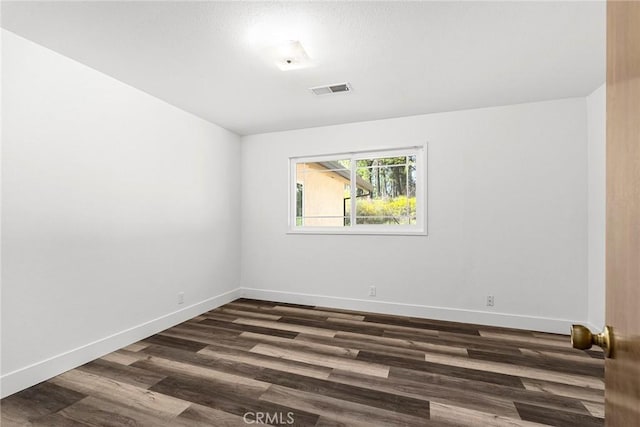 spare room featuring dark wood finished floors, baseboards, and visible vents