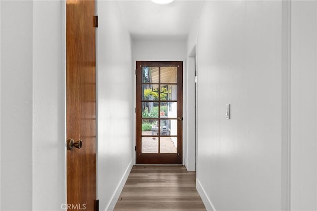doorway featuring baseboards and light wood-style flooring
