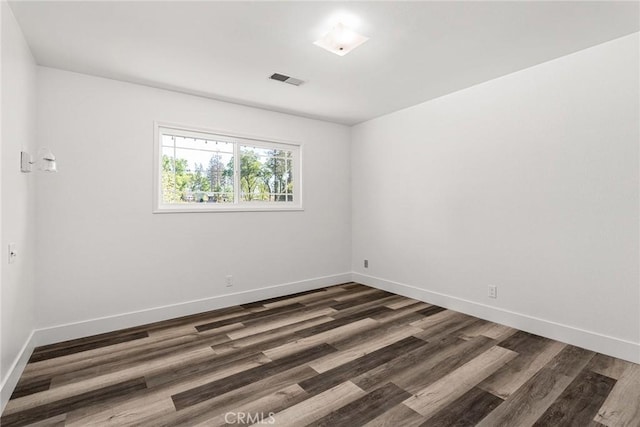 unfurnished room with visible vents, baseboards, and dark wood-style flooring