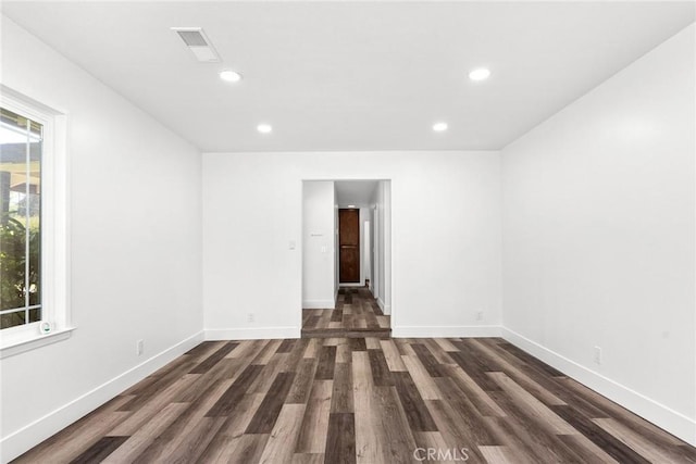 empty room with baseboards, visible vents, and dark wood-type flooring